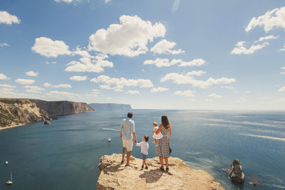 A young family of 5 standing on a cliff, looking at the infinite ocean.