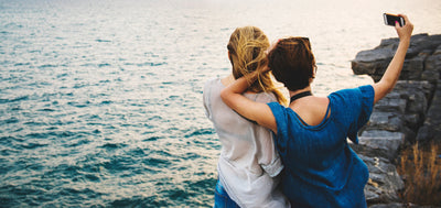 two girlfriends posing for a selfie while gazing at the see