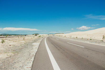 empty road, crossing the desert, blue skies ahead.